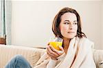 Woman having cup of juice on sofa