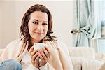 Woman having cup of coffee on sofa