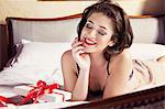 Woman in lingerie with gift on bed