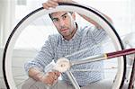 Man fixing bicycle wheel indoors