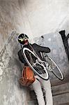 Man carrying bicycle up staircase