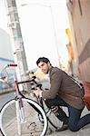 Man locking bicycle on city street