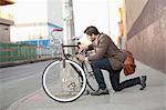 Man locking bicycle on city street