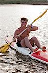 Smiling man rowing kayak in lake