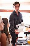 Waiter serving women in cafe