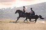 Couple riding horses in rural landscape