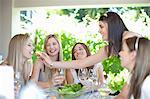 Woman feeding friend at table