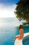 Brazil, Bahia, Salvador, model in an infinity swimming pool overlooking the Baia de Todos os Santos, All Saints Bay,  wearing a blue and white bikini MR