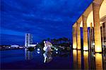 South America, Brazil, Brasilia, Distrito Federal, night view of Oscar Niemeyers Palacio de Itamaraty in Brasilia, reflected in the surrounding lake landscaped by Roberto Burle Marx with the Congresso Nacional behind