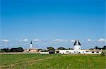 France, Charente Maritime, Ile de Re.  View across a field towards  the tower of an old windmill now converted into a house just outside the village of Ars en Re.
