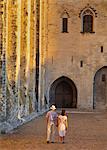 France, Provence, Avignon, Palais de Papes, Man and woman walking down cobbled road MR