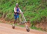 A young boy rides his homemade wooden bicycle, Uganda, Africa