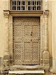 old brown medieval wooden door on stone building in the small village of Saint-Antoine-l'Abbaye, France