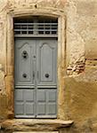 old grey blue wooden door on stone building in the small medieval village of Saint-Antoine-l'Abbaye, France