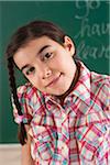 Head and Shoulders Portrait of Girl in front of Chalkboard in Classroom