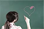 Girl Drawing Heart on Chalkboard in Classroom