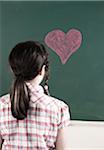 Back of Girl Looking at Heart drawn in Chalk on Chalkboard in Classroom