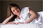 Portrait of smiling woman lying on her bed in her bedroom.