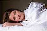 Portrait of woman lying on her bed in her bedroom.