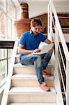 Young man sitting on a stairs at home working with laptop computer