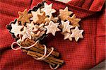 Decorative, sparse christmas arrangement with greeting card copyspace for "Merry Christmas"-text. Ginger cookies and cinnamon sticks arranged on a red cloth.