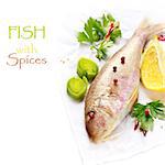 Fresh goatfish with lemon, leek and spices on white.
