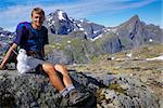 Young active man with small snowman hiking on Lofoten islands in Norway on sunny day