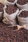 Coffee in burlap bags and spilled on the table - closeup