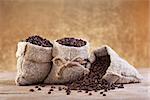 Roasted coffee beans in burlap bags on old table