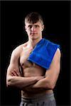 Young muscular man page with a blue towel on a black background