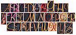 complete English alphabet  in ornamental script wood type - a  collage of 26 isolated letterpress printing blocks stained by color and black ink