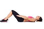 Young woman in gym clothes lying on her back on the floor doing a workout, studio portrait on white