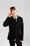 Studio portrait of serious looking young boy in black suit saluting