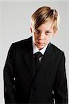 Studio portrait of serious looking young boy wearing black suit