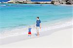 father and his little kid walking at the perfect caribbean beach