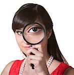 Cute young woman holding a magnifying glass over her eye