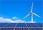 Solar panels and wind turbine against blue sky