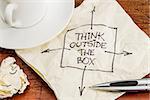 think outside the box - black pen drawing on a cocktail napkin with a coffee cup on a table