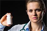 Medical doctor woman showing medicine bottle on black background