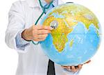 Closeup on medical doctor woman listening globe with stethoscope