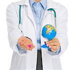 Closeup on medical doctor woman holding pills and globe
