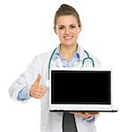 Smiling medical doctor woman showing laptop and thumbs up