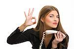 Portrait of attractive young business woman gesturing okay sign after successful deal on phone over white background.