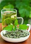 Nettle and freshly made nettle tea in glass cup.