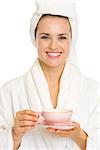 Happy young woman in bathrobe holding cup of tea