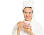 Smiling young woman in bathrobe holding cup of coffee