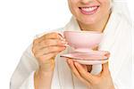 Closeup on smiling young woman in bathrobe with cup of tea