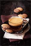 Cup of coffee and chocolate cookies on a dark wooden background.