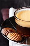 Cup of coffee and chocolate cookies on a dark wooden background close-up.