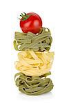 Fettuccine nest pasta with tomato cherry on top. Isolated on white background